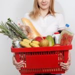 Young woman with goods in basket. The girl made a purchase. Girl holding a basket of groceries. Vegetables